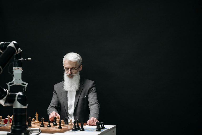 An elderly man competes against a robotic arm in a chess game, symbolizing the intersection of technology and strategy.